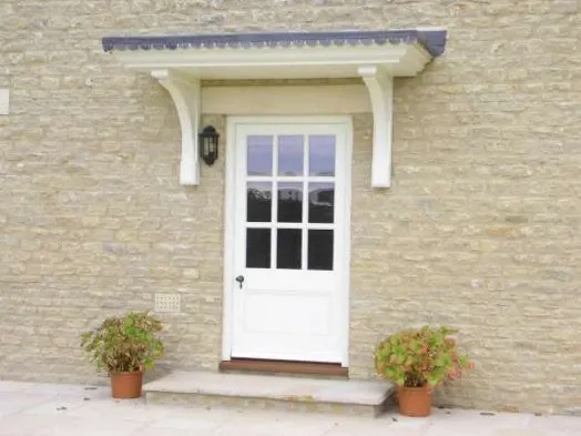 A pale exterior door set into a stone and brick wall.