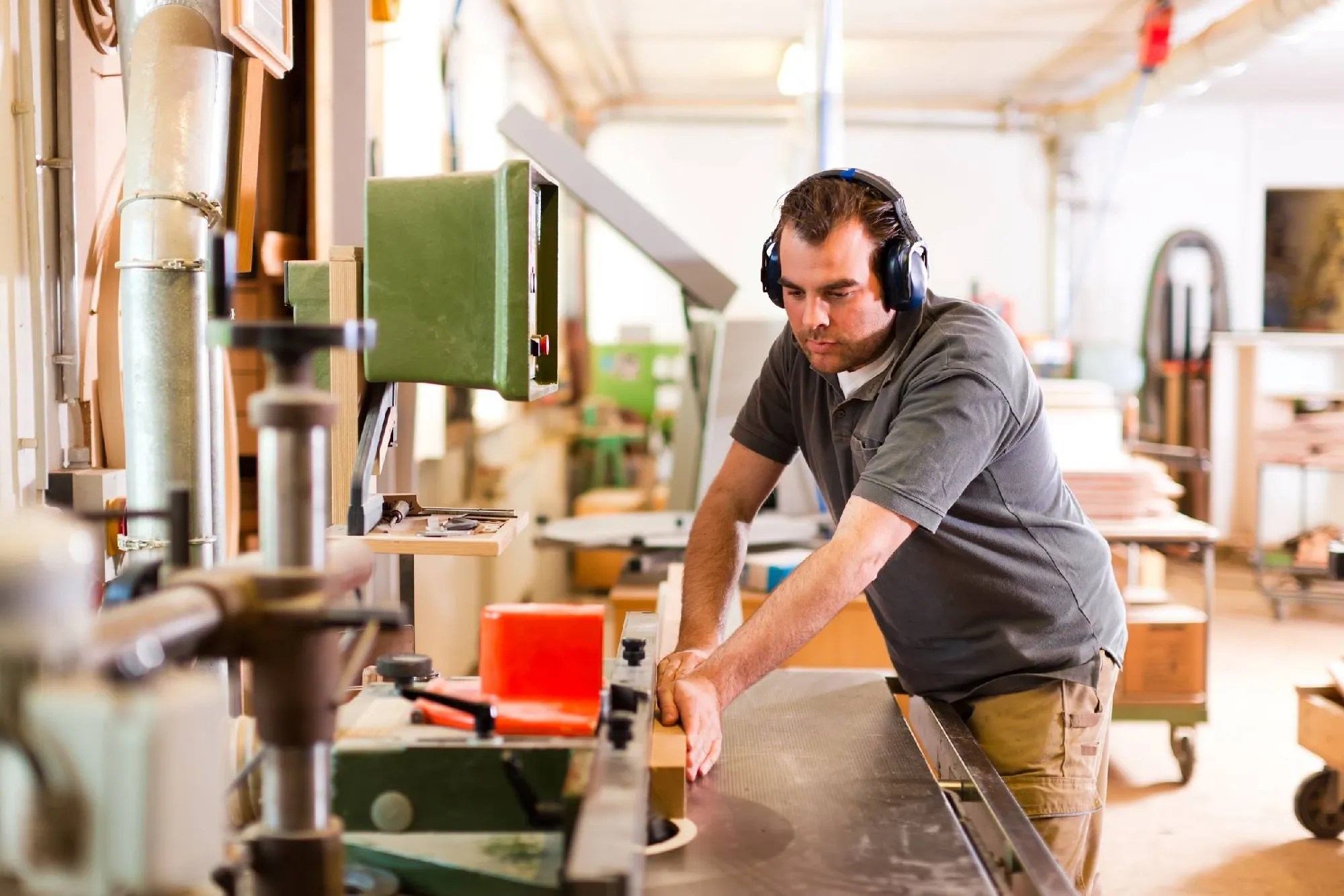 A craftsperson working at woodworking machinery in a bright workshop.
